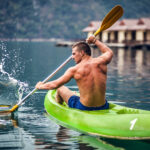 Strong young man in kayak on the picturesque lake in Thailand.